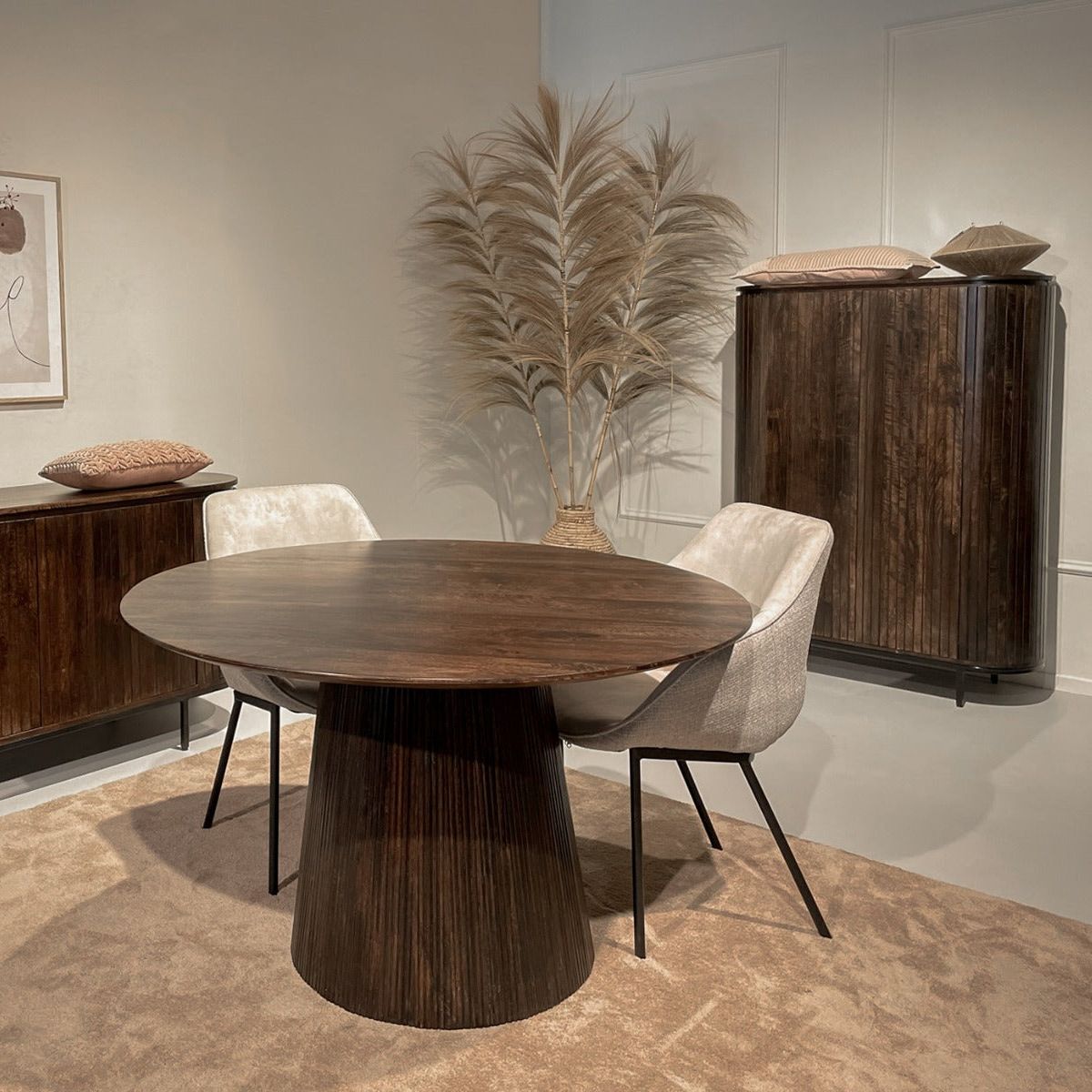 Donker Noor dressoir naast een ronde eettafel in een warm ingerichte eetkamer