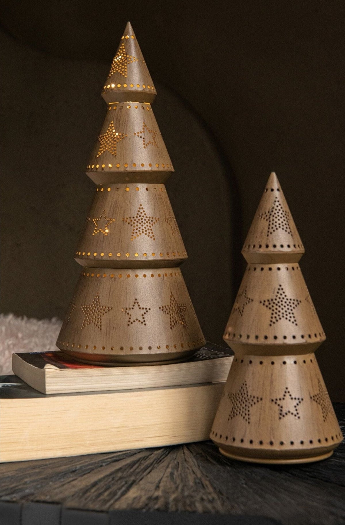 Kerstboom Led Sterren van J-Line, drie bomen op een stapel boeken in een donkere nis