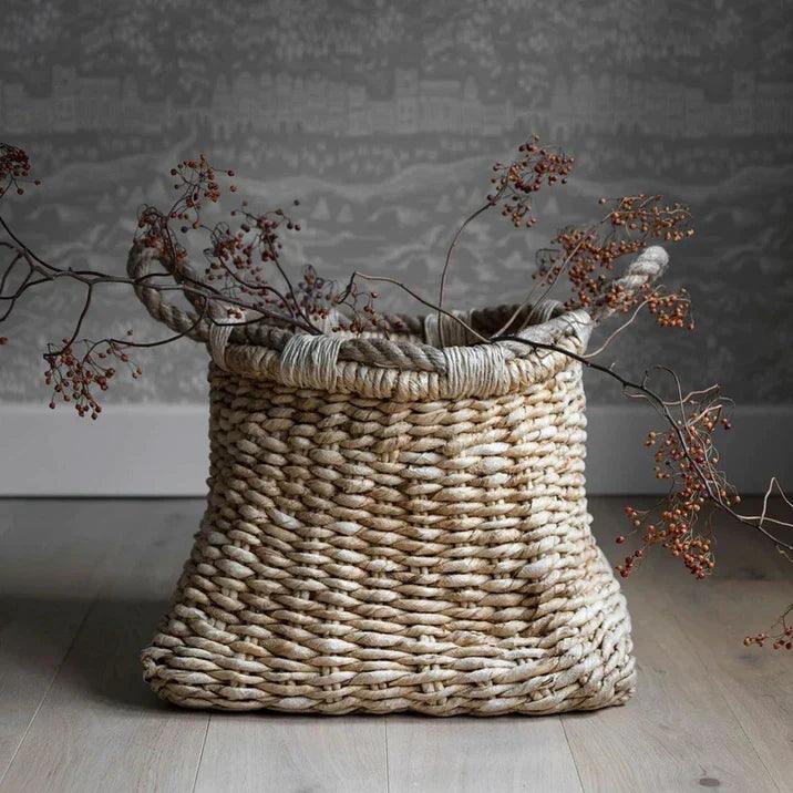 Mand Palette Large van MUST Living, de mand gevuld met plaids naast een fauteuil