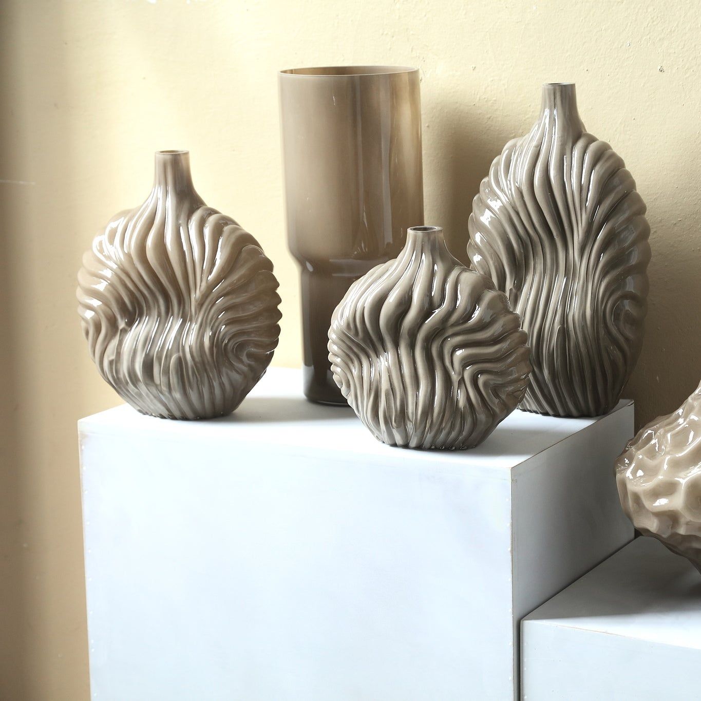 Set Van 3 Kelline Glazen Vazen Ribbel van PTMD, de taupe vaas small in een woonkamer