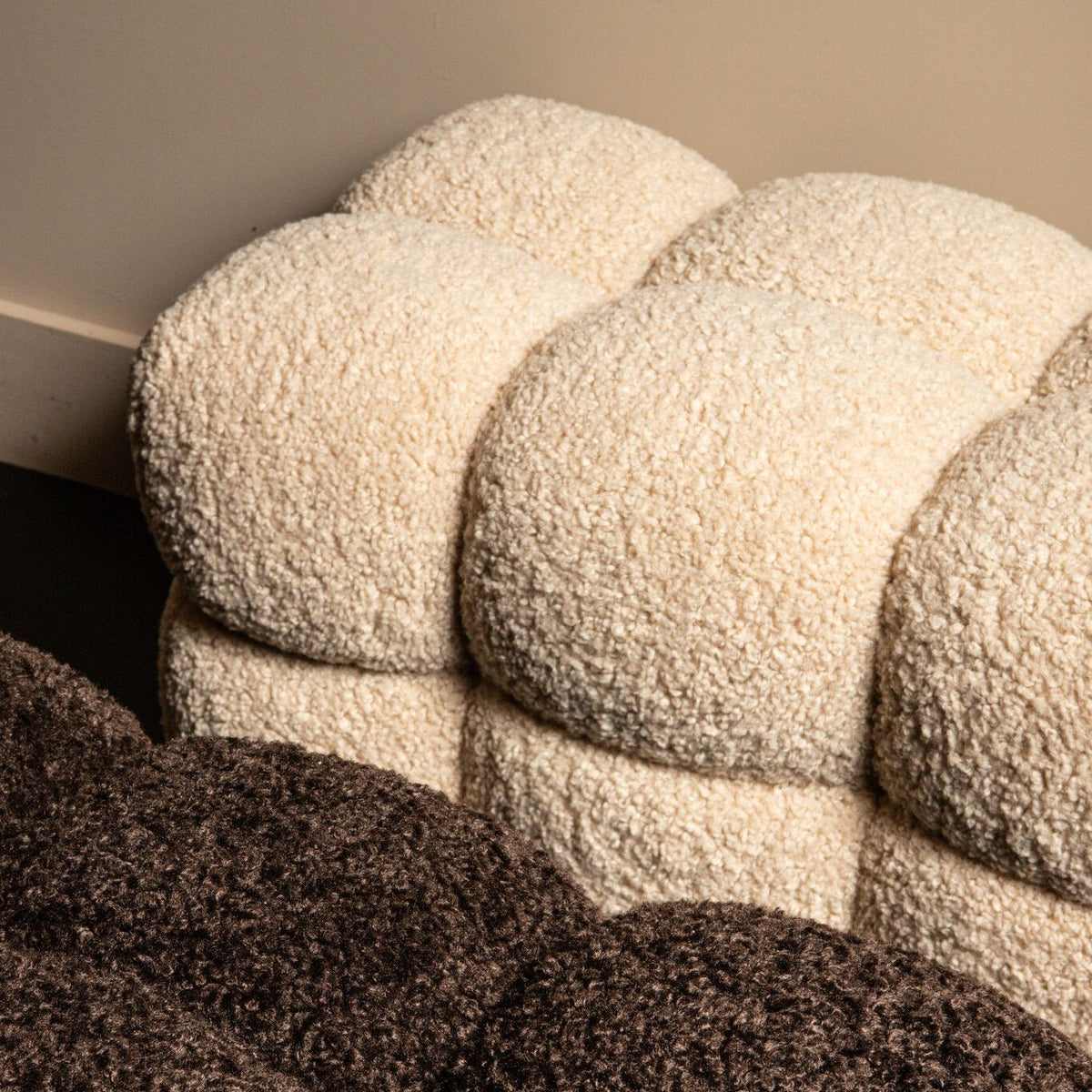 Detail van de gekrulde beige teddy stof en de ronde vakken van het bankje