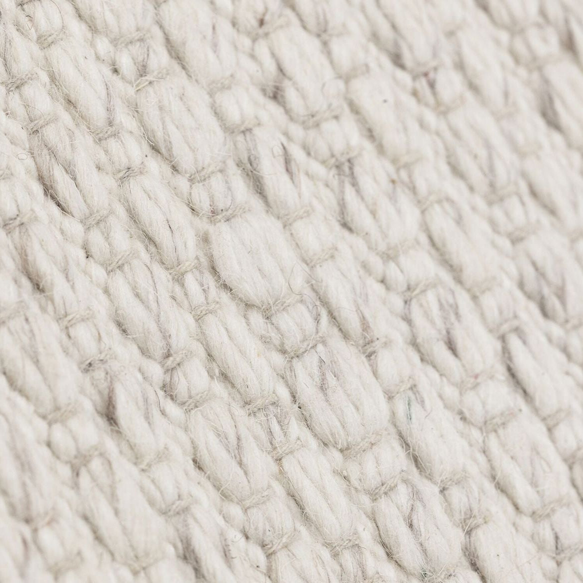 Vloerkleed Nirvana van MUST Living, detailfoto van de dikke gevlochten wolstructuur in ivoor