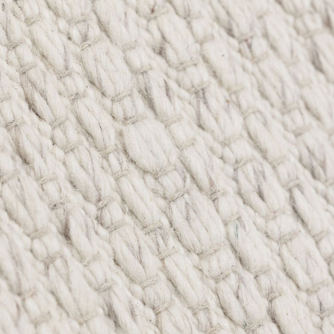 Vloerkleed Nirvana van MUST Living, detailfoto van de dikke gevlochten wolstructuur in ivoor