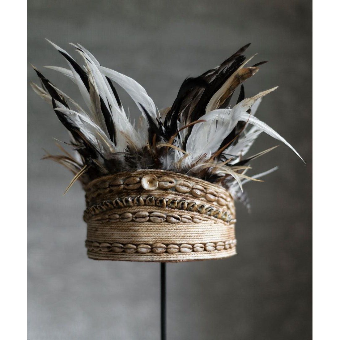 Balinese helm van MUST Living met schelpen en veren gestyled aan een lichte muur