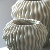 Barren Beige Cement Round Vase 3D Wavy Pattern L van PTMD, sfeerfoto op een dressoir