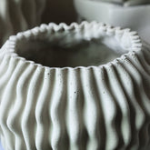 Barren Beige Cement Round Vase 3D Wavy Pattern L van PTMD, sfeerfoto gecombineerd met de witte Barren vaas