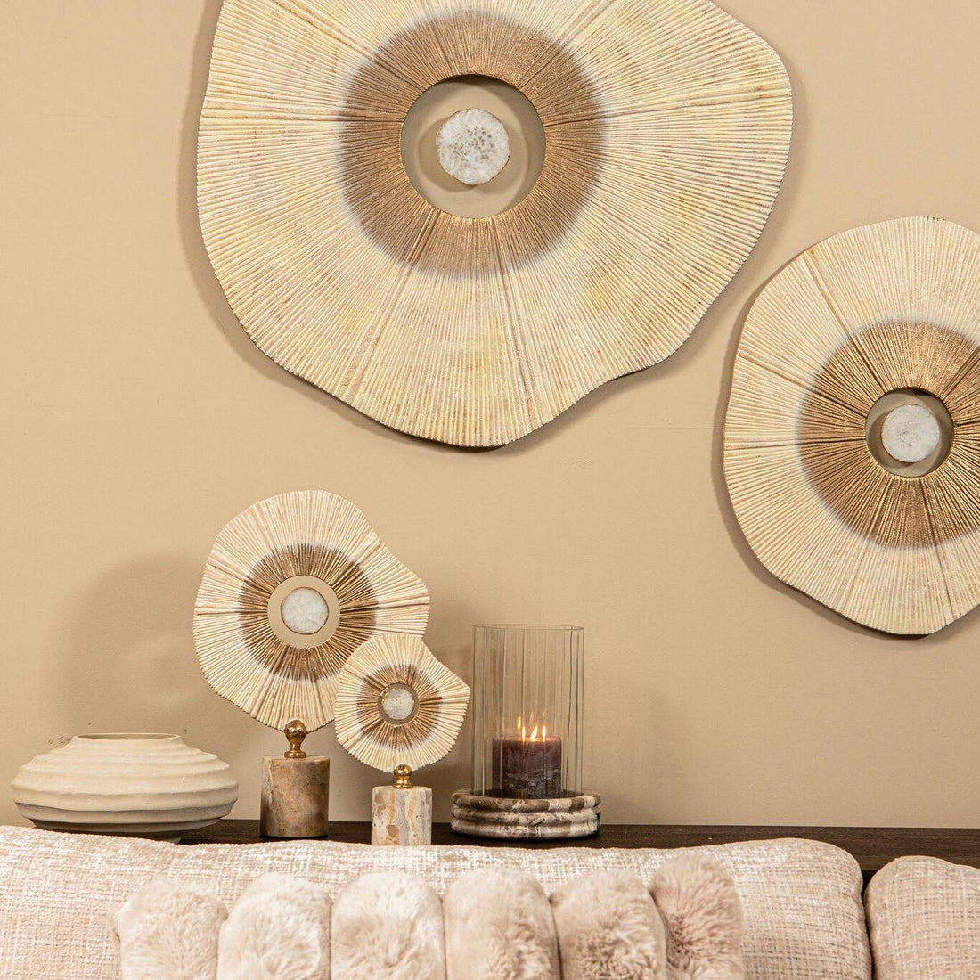 Rella beelden van PTMD in beige met goud op een dressoir, gecombineerd met wanddecoratie, een vaas en een windlicht