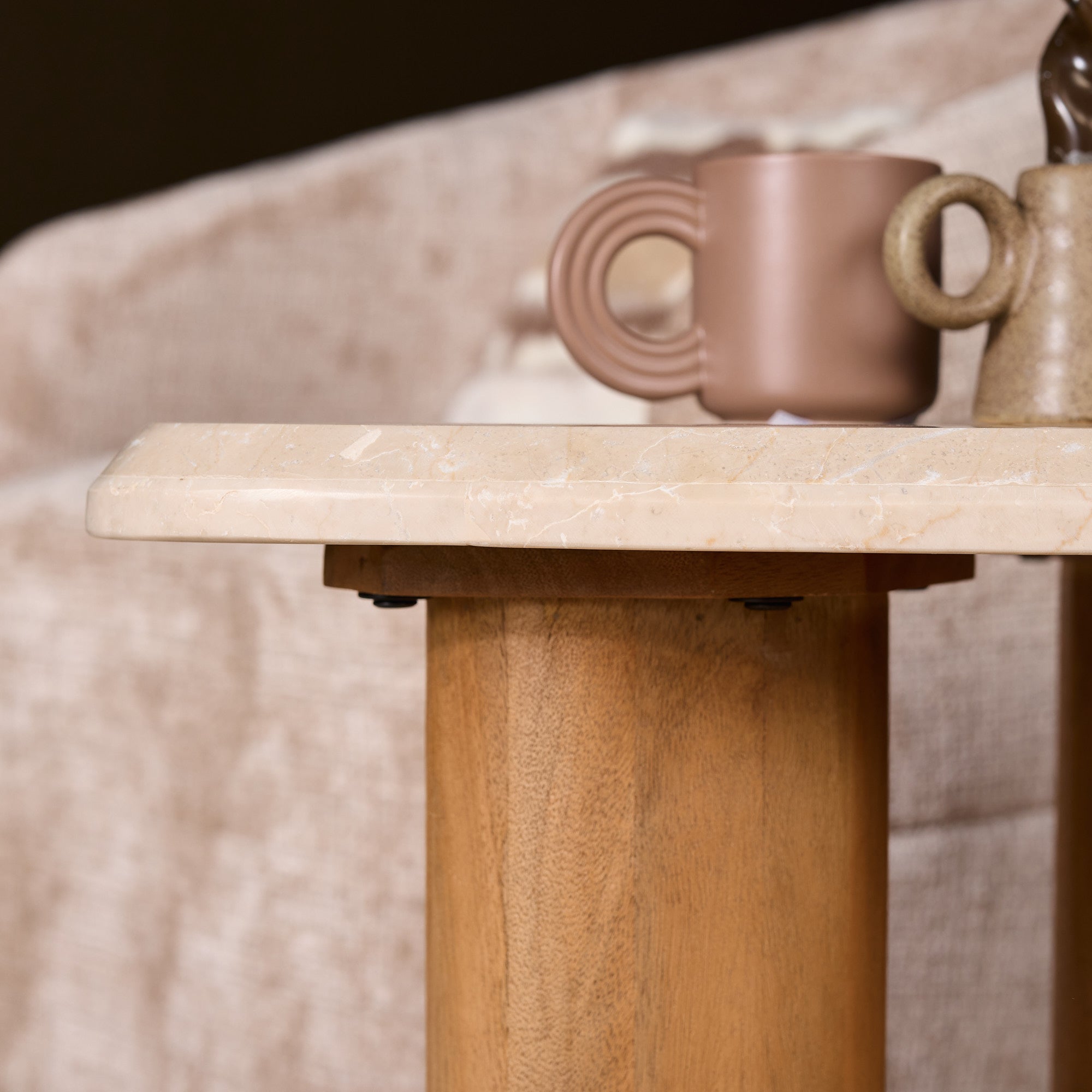 Bijzettafel Nuvé van Starfurn gestyled met een kaars en een boek op het beige marmer