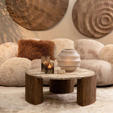 Beige Curvae bank van PTMD gestyled met ronde wanddecoratie, houten salontafel en roestbruin kussen