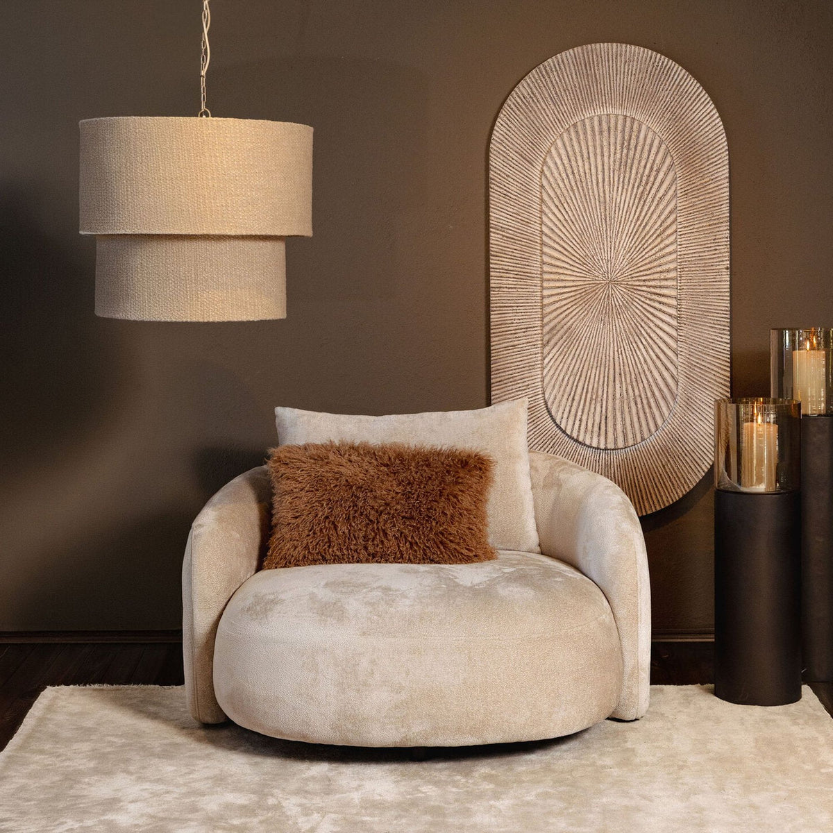 Devi hanglamp in taupe van PTMD boven een ronde fauteuil in een warme woonkamer