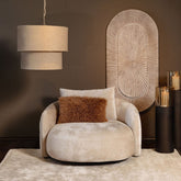 Devi hanglamp in taupe van PTMD boven een ronde fauteuil in een warme woonkamer