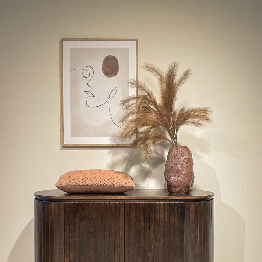 Walnut Noor dressoir tegen een lichte wand met droogbloemen en een lijst erboven