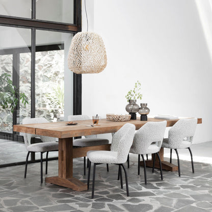 Eetkamerstoel Bloom van MUST Living in licht grijs bouclé aan een houten eettafel in een lichte eetkamer