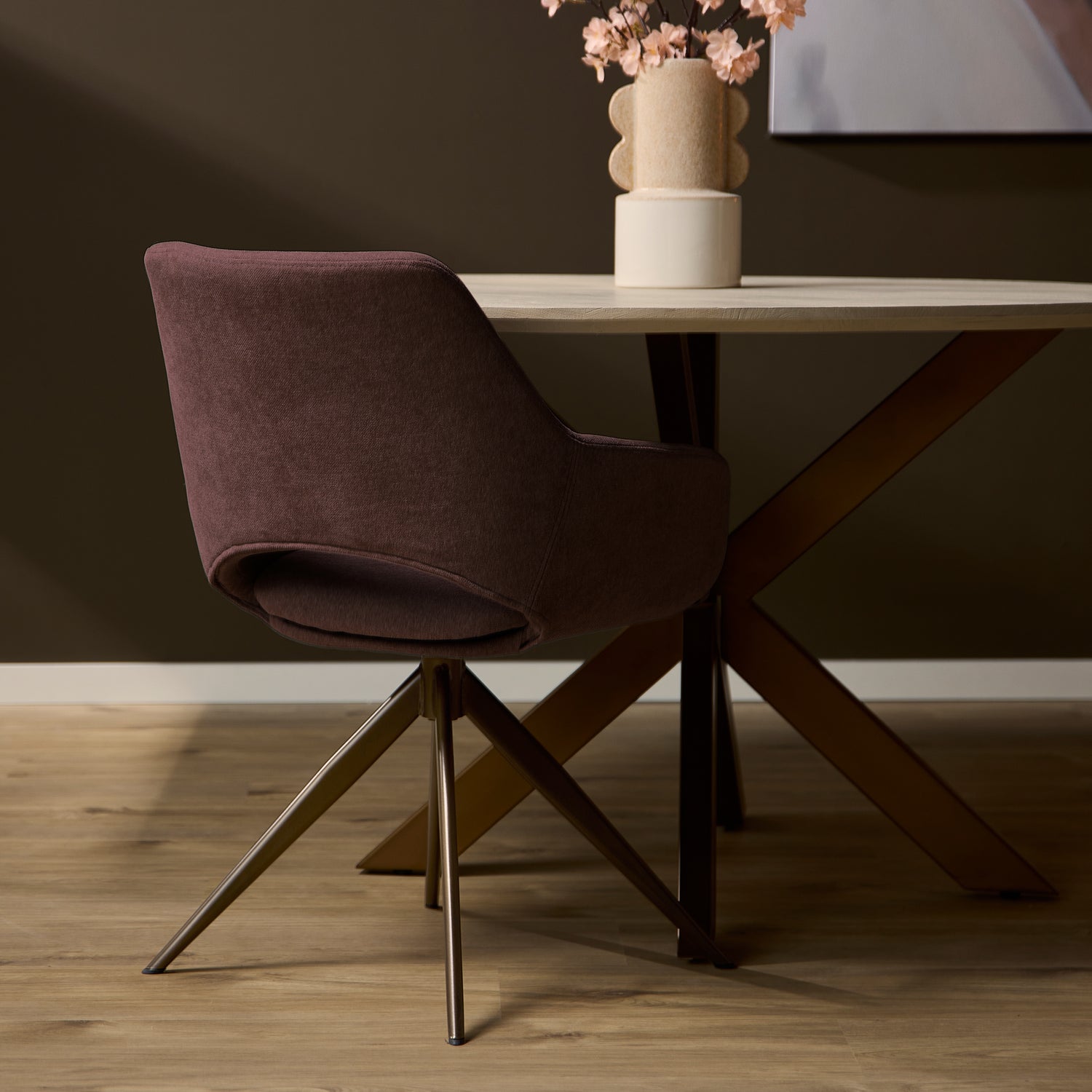 Achterzijde van de roze eetkamerstoel Daisy aan een eettafel met houten vloer