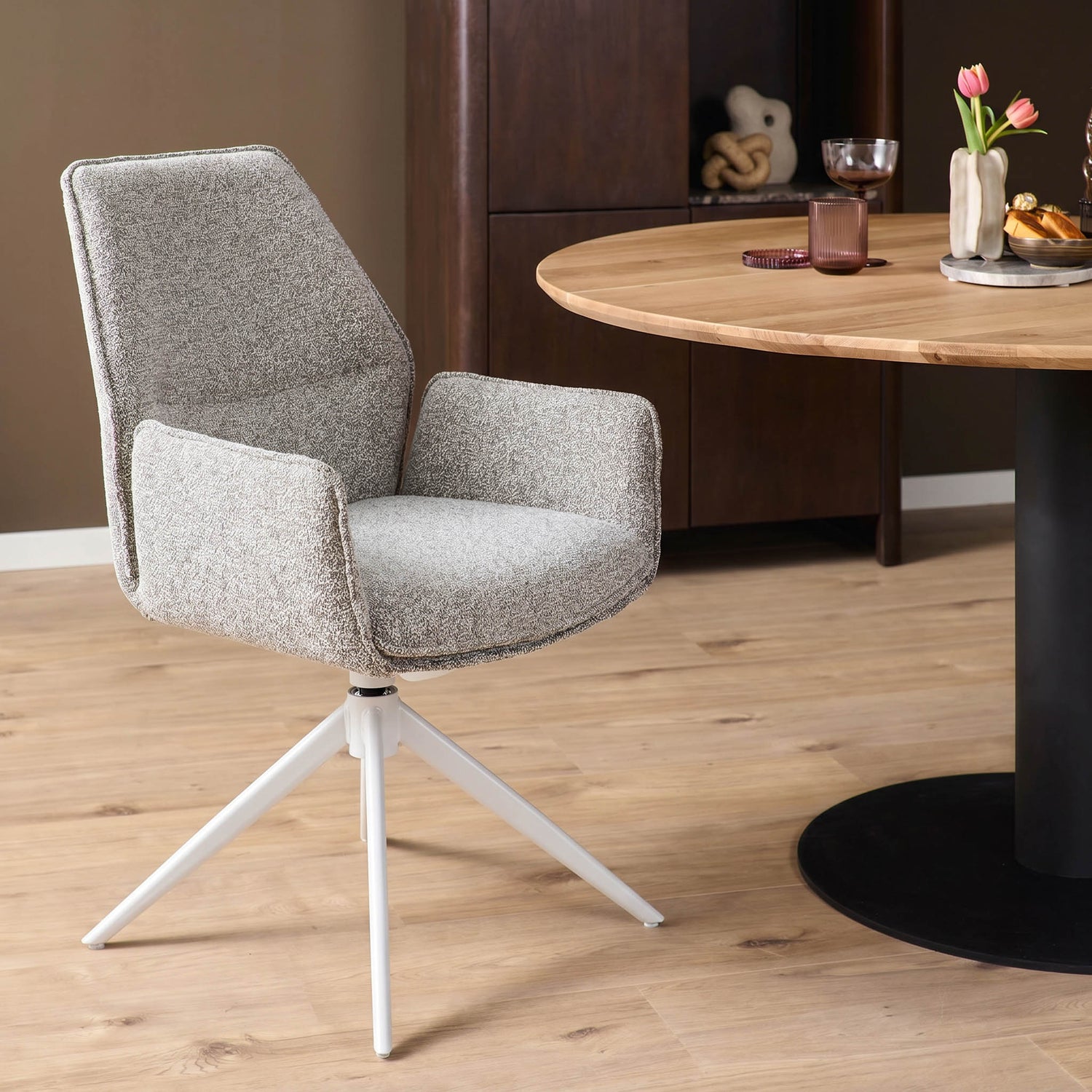 Beige eetkamerstoel Hera met armleuningen aan een ronde houten eettafel