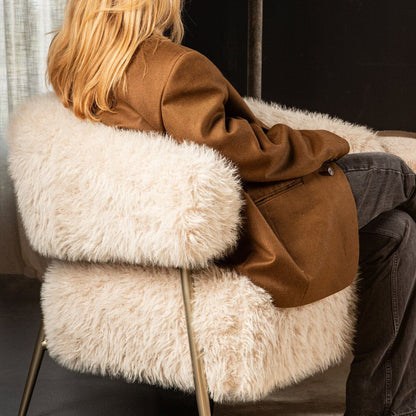 Hair Cream fauteuil van PTMD met champagnekleurig onderstel in een woonkamer
