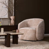Fauteuil Yara van Starfurn in beige naast een bank met kussens en een plaid