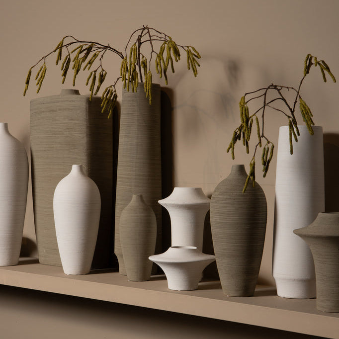 Beige Cavinn flesvaas van PTMD gestyled met een enkele tak op een houten dressoir