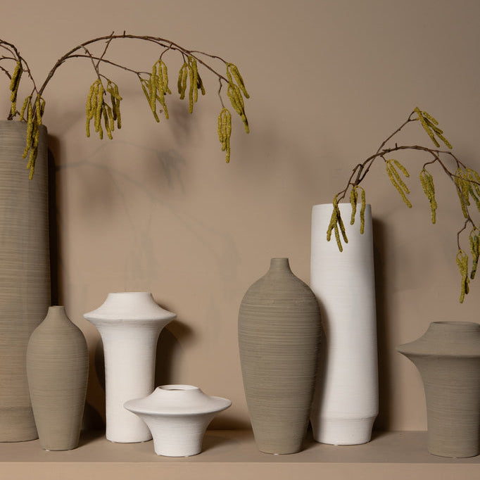 Beige Cavinn vaas van PTMD in een sfeerbeeld naast kaarsen en woonaccessoires