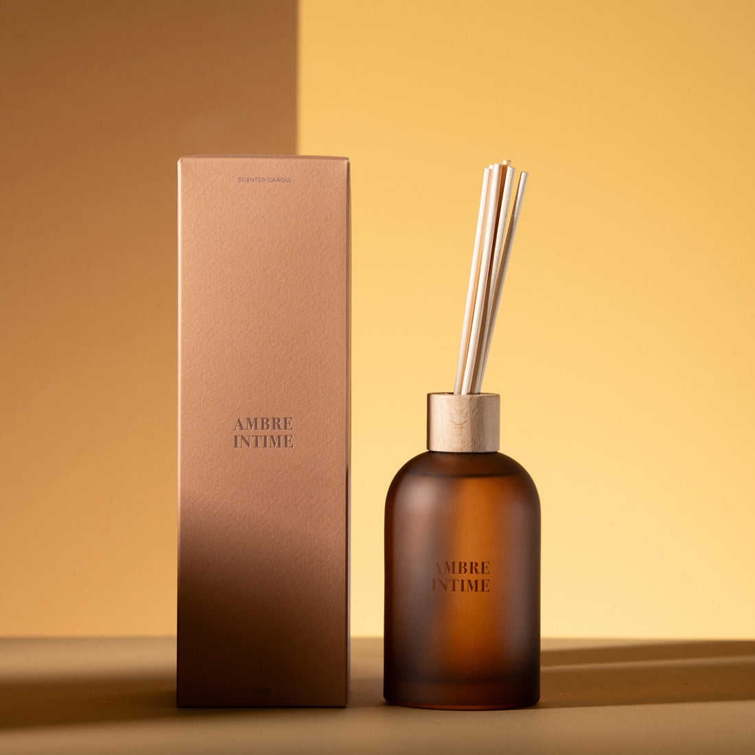 Geurstokjes Accords Essentiels Ambre Intime 250ml van J-Line met bijpassende doos in een sfeervolle okerkleurige setting