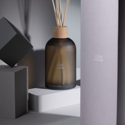 Geurstokjes Accords Essentiels Cuir Désir 550ml van J-Line op decoratieve blokken in een warme sfeerfoto