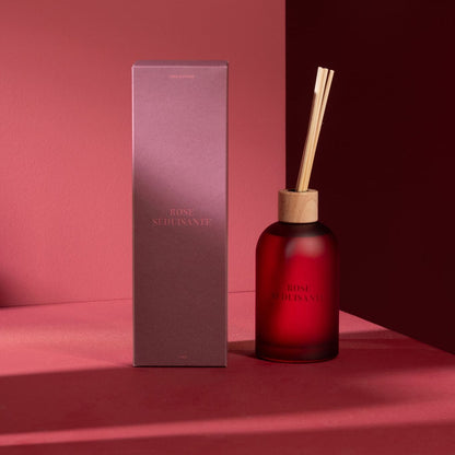 Geurstokjes Accords Essentiels Rose Séduisante 250ml van J-Line met bijpassende doos in een sfeervolle rode setting