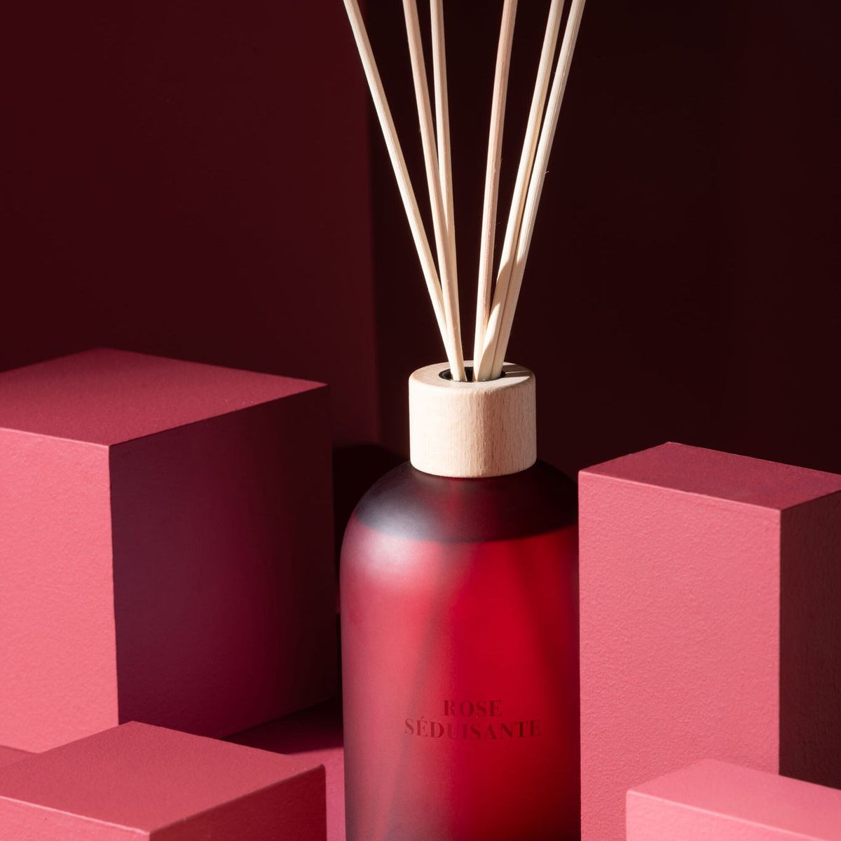 Geurstokjes Accords Essentiels Rose Séduisante 550ml van J-Line op decoratieve blokken in een warme sfeerfoto