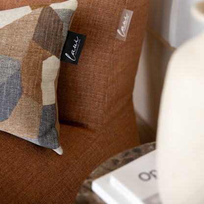Het Stone Camel kussen van Laui Lounge op een bank in een warm interieur