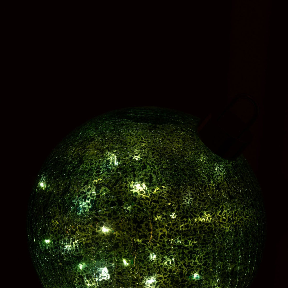 Grote turquoise kerstbal van J-Line die met ledverlichting warm gloeit in een donkere kamer