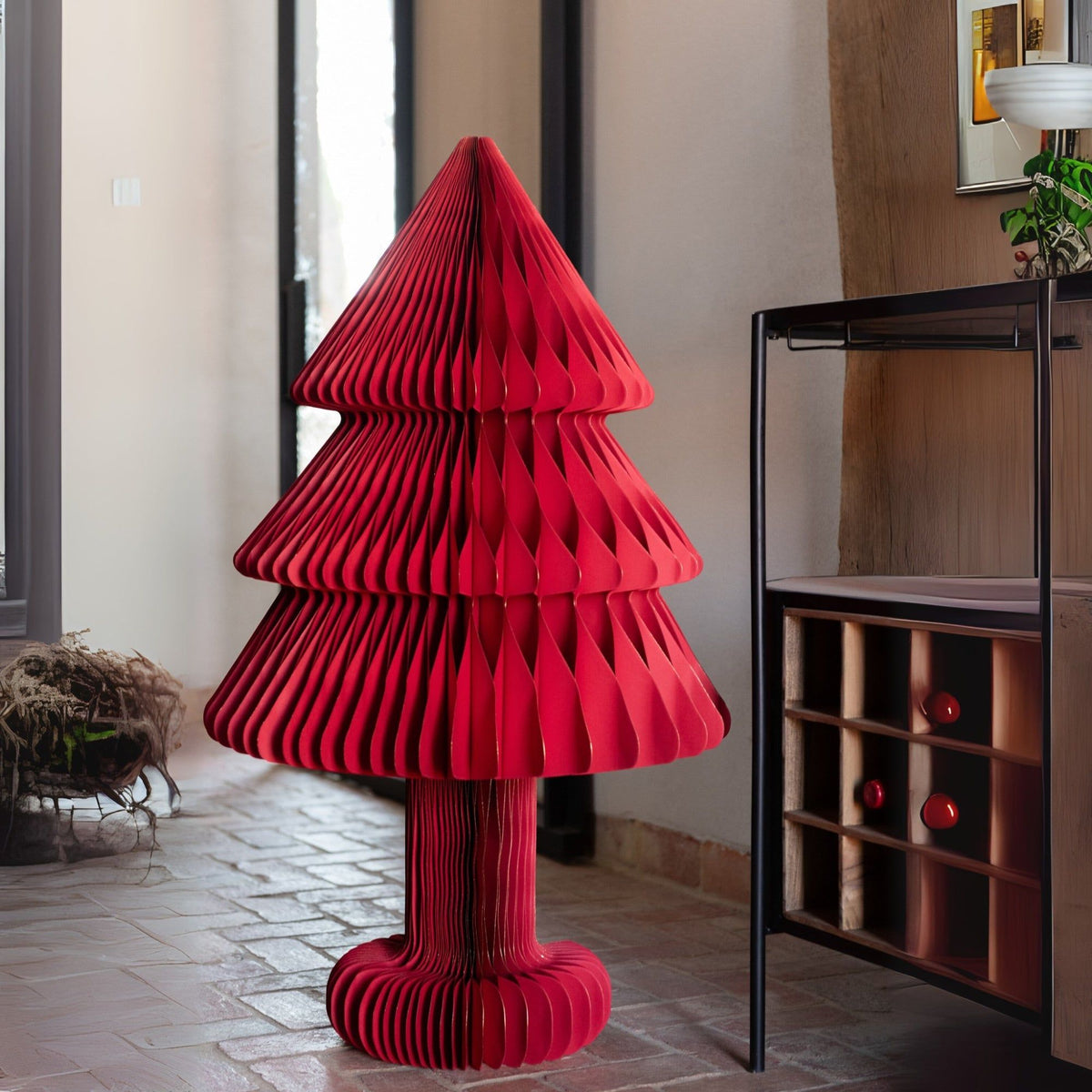 Kerstboom Vouwbaar Papier Kerstrood Large van J-Line, in een hal naast een houten kast