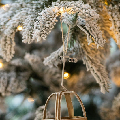 Beige kabelbaancabines van J-Line hangend in een besneeuwde kerstboom met lichtjes