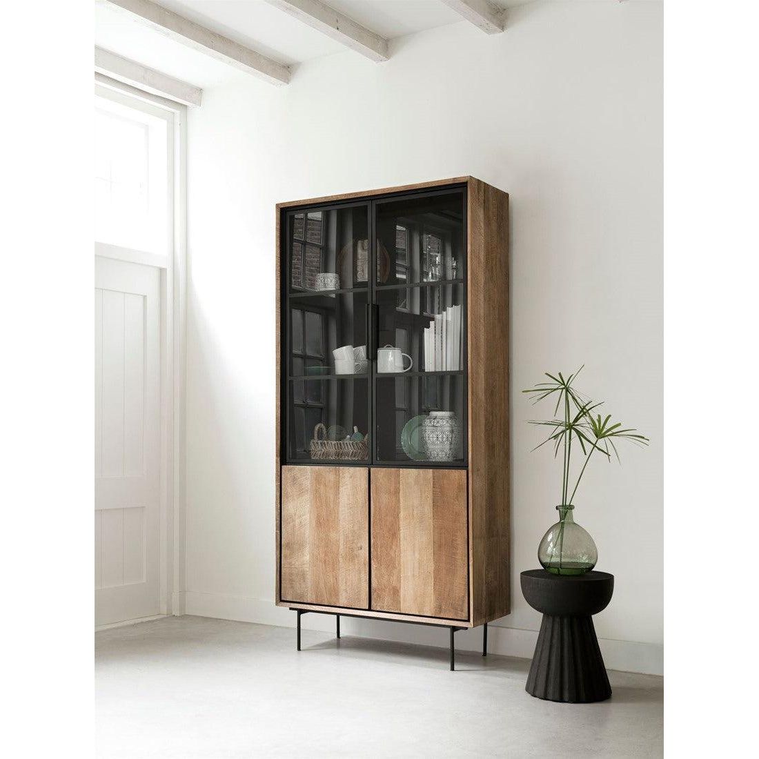 Kruk Trophy van MUST Living in een interieur, zwart krukje naast een bank met een plant erop