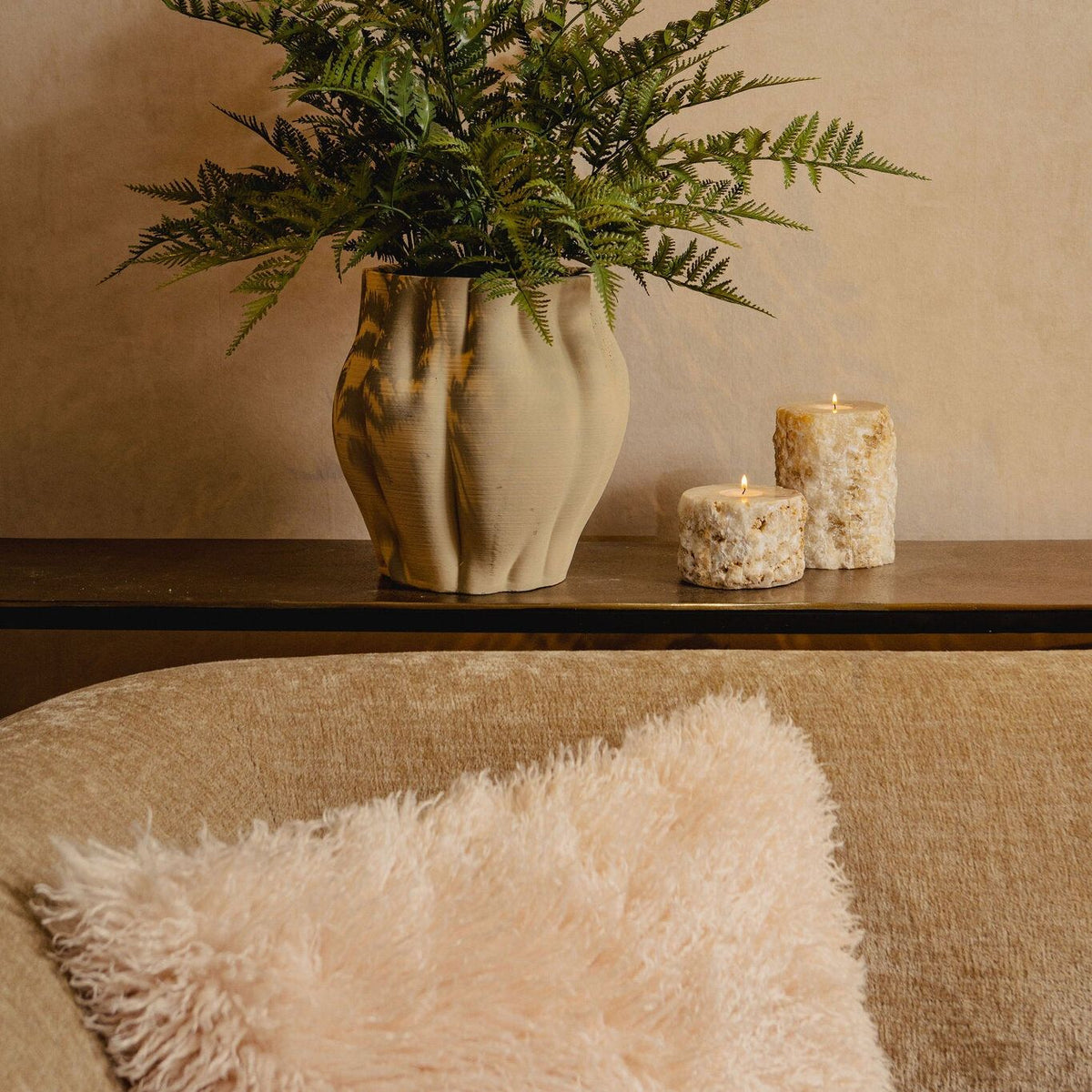 Kunstvaren van PTMD in zwarte pot gestyled op een kast in een lichte woonkamer