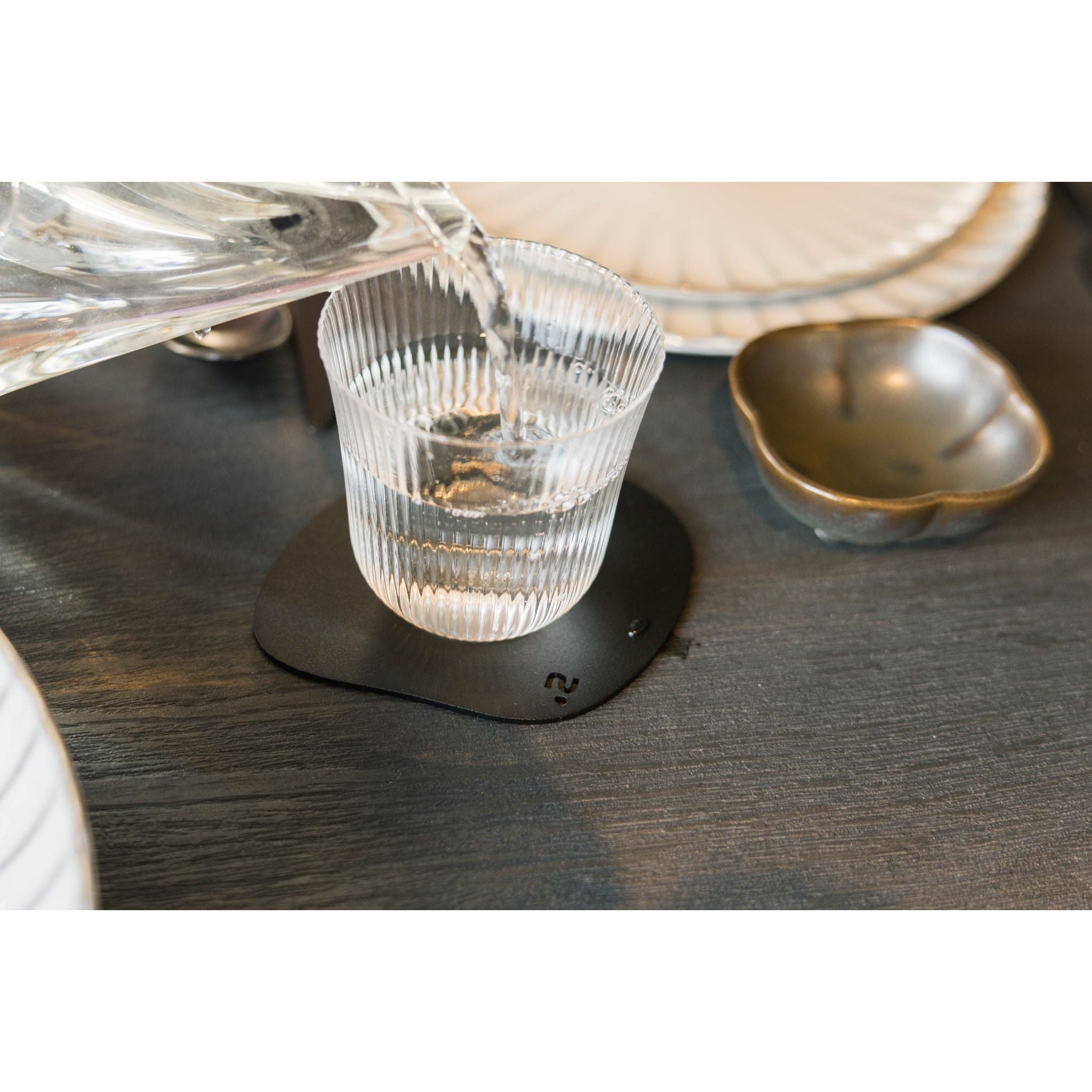 Orga onderzetters van Steelful op tafel, matzwart gepoedercoat staal in een moderne setting