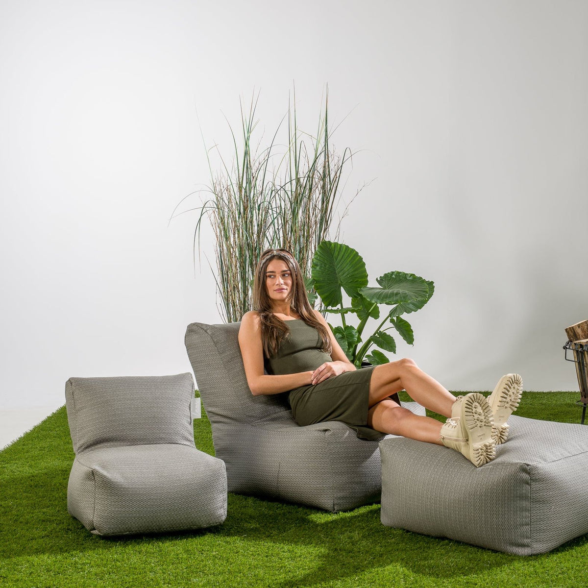 Sfeerbeeld met de Square Pouf Stone Grey van Laui Lounge als voetenbank in de tuin