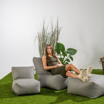 Sfeerbeeld met de Square Pouf Stone Grey van Laui Lounge als voetenbank in de tuin