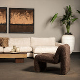 Oslo teddy fauteuil in bruin naast een witte bank en salontafel in een woonkamer