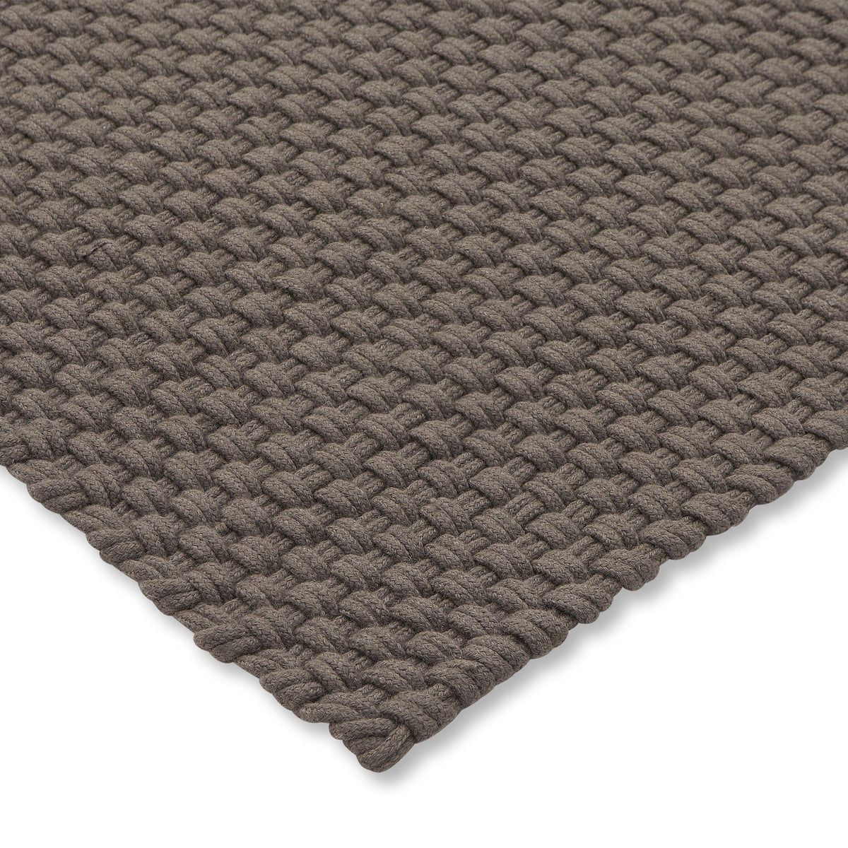 Het grote Nomad tapijt in Grey Taupe onder een buitenbank en fauteuils