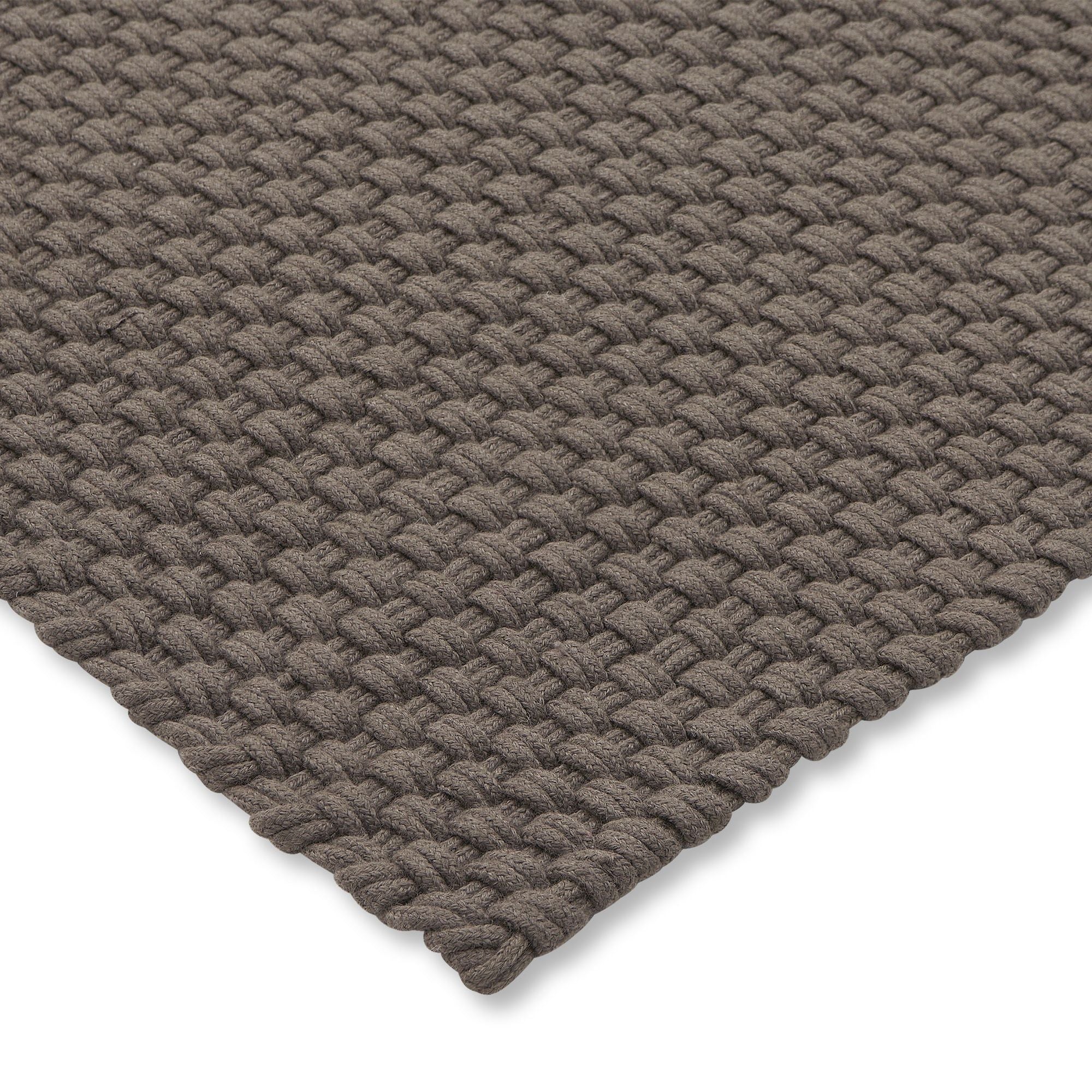 Het grote Nomad tapijt in Grey Taupe onder een buitenbank en fauteuils