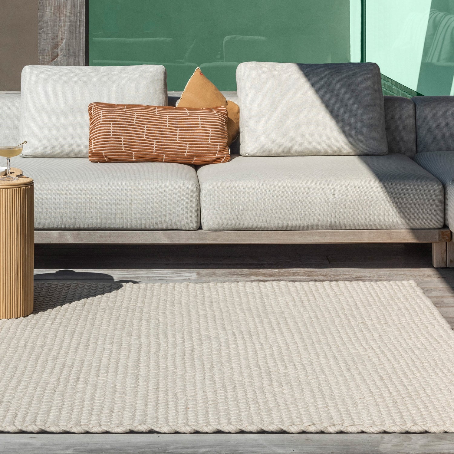 Het zandkleurige Nomad outdoor vloerkleed van Laui Lounge in een tuinsetting