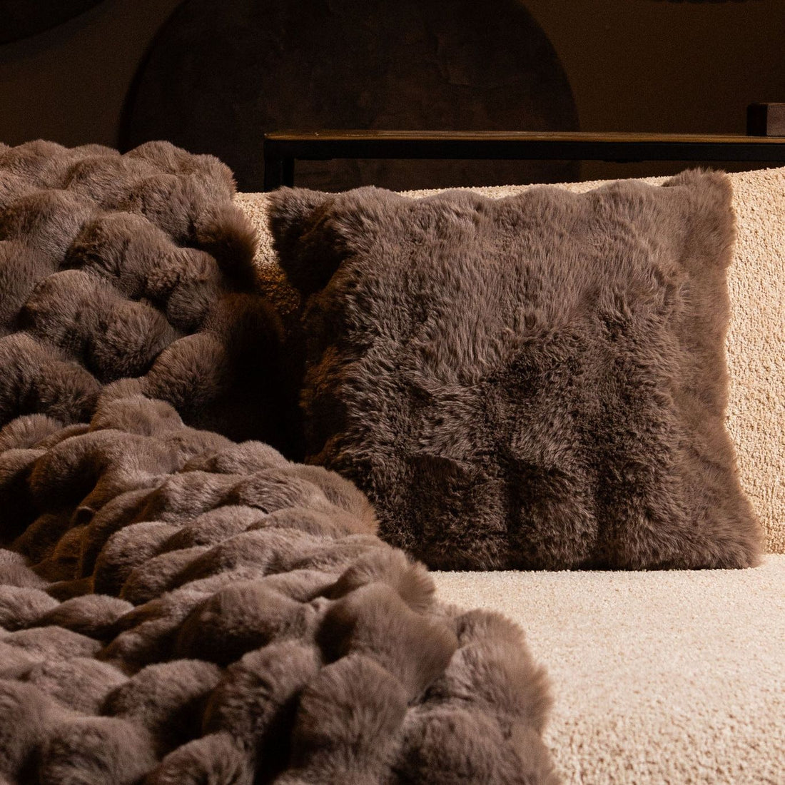 Taupe Dunae plaid van PTMD over een bed als sprei