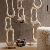 Ronde poef Hair Beige van PTMD in een lichte woonkamer naast een fauteuil