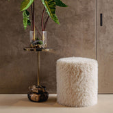 Beige ronde poef van PTMD als voetenbank in een warm interieur met plaid