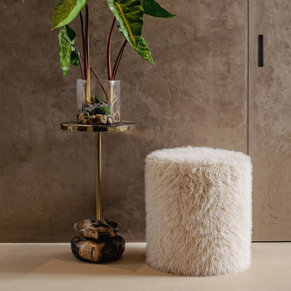 Beige ronde poef van PTMD als voetenbank in een warm interieur met plaid