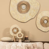 Rella beelden van PTMD in beige met goud op een dressoir, gecombineerd met wanddecoratie, een vaas en een windlicht
