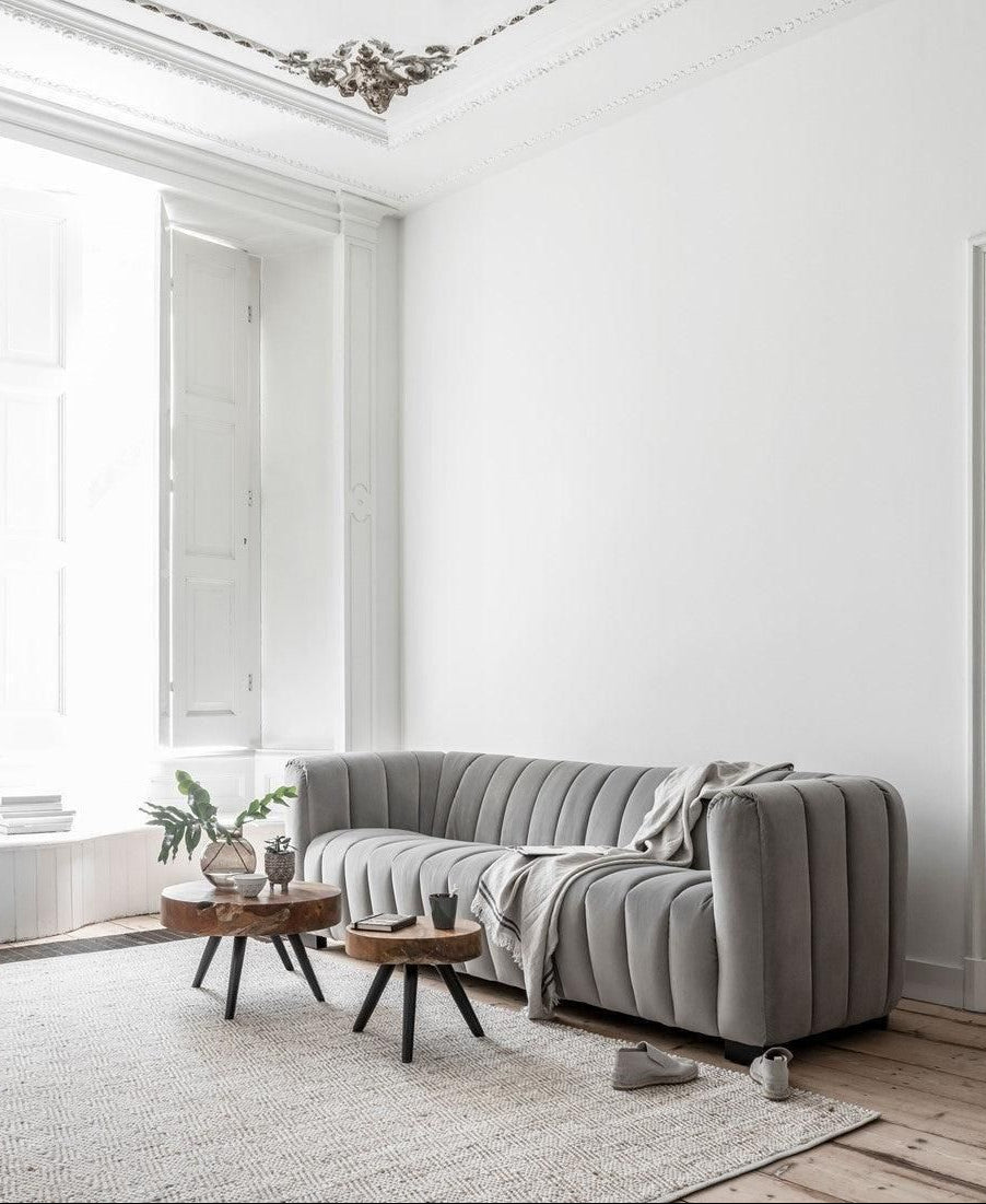 Salontafel Disk Large van MUST Living in een woonkamer, rond teakhouten blad naast een lichte bank