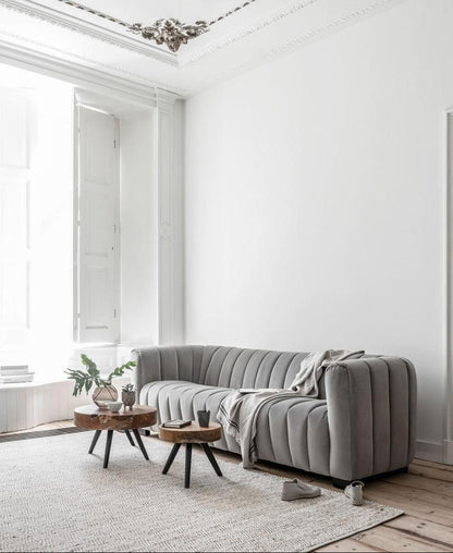 Salontafel Disk Large van MUST Living in een woonkamer, rond teakhouten blad naast een lichte bank