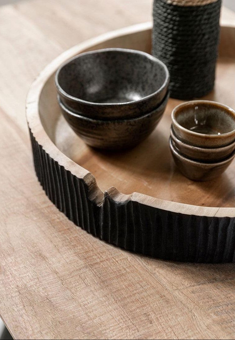 Schaal Groove van MUST Living, zwart gebrande houten schaal gestyled op een tafel in een woonkamer