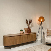 Noor tv-meubel in Pecan in een woonkamer met vloerlamp en fauteuil