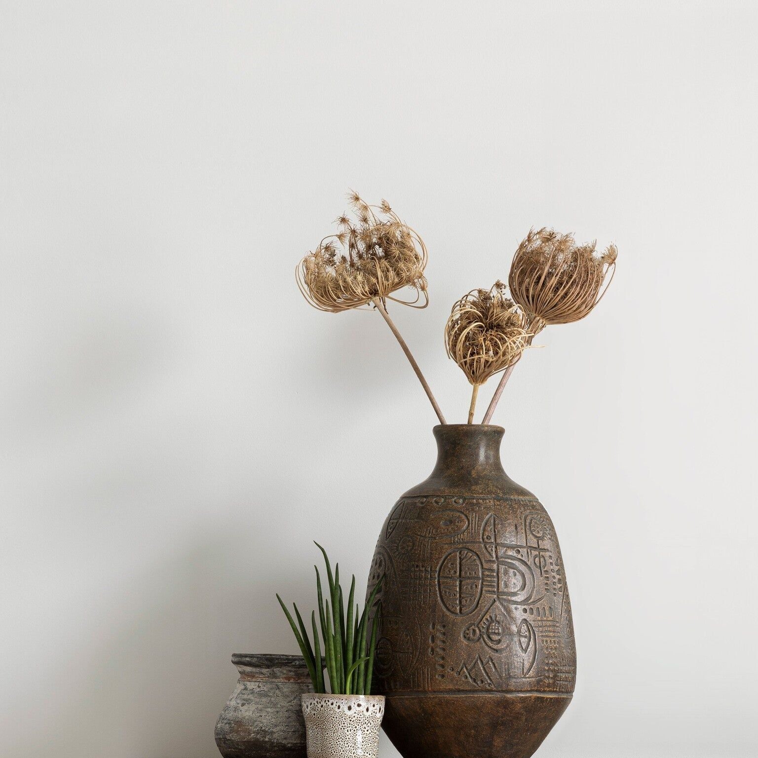 Vaas Faro van MUST Living op een eiken dressoir met droogbloemen naast twee kleine potjes